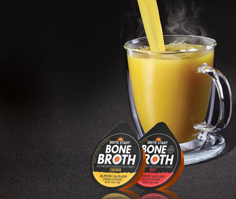 Brite start bone broth cup and saucer set with clear glass mug, black base plate, yellow straw.