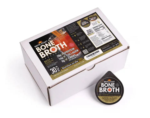 White cardboard box with black and gold label containing brite start bone broth, alongside a single dark brown, teardrop-shaped broth pod.